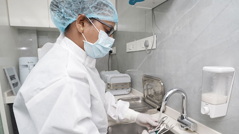  A tray of metal dental instruments being placed into an autoclave for sterilization in at the smile spa dental clinic juhu mumbai