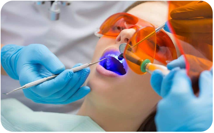 Patient undergoing dental filling treatment, the patient is wearing eye goggles to protect her eye from exposure to light